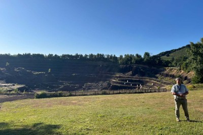 Paysage d'une ancienne carrière volcanique avec des formations rocheuses, entourée de végétation et sous un ciel bleu.