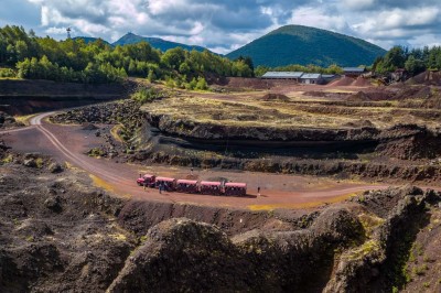Paysage d'une ancienne carrière volcanique avec des formations rocheuses, entourée de végétation et sous un ciel bleu.