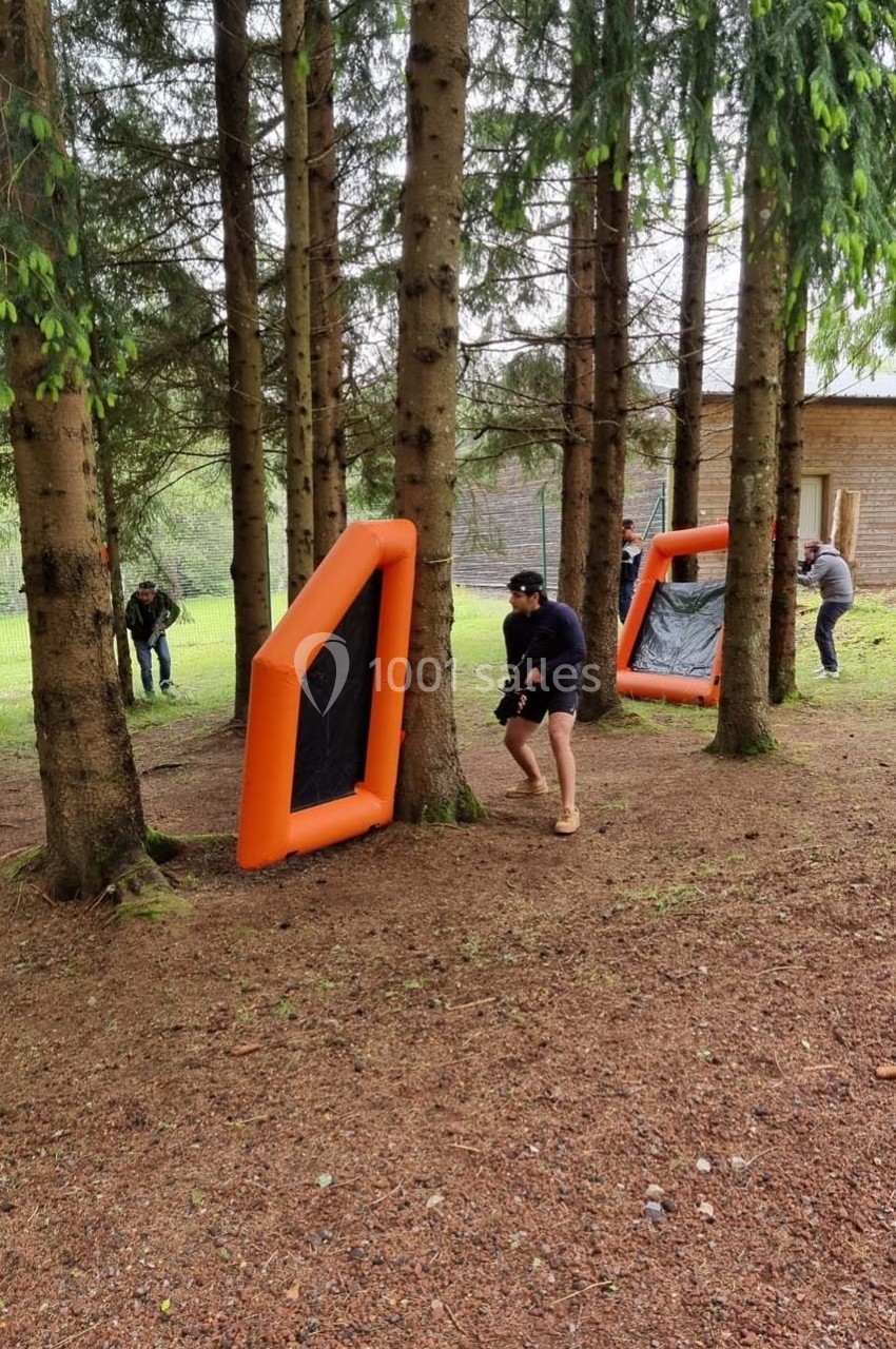 Personnes jouant à un jeu d'extérieur avec des obstacles gonflables orange dans une forêt.