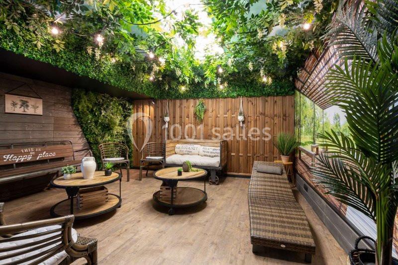 Espace intérieur décoré avec des plantes, mobilier en bois et rotin, éclairage suspendu créant une ambiance naturelle.