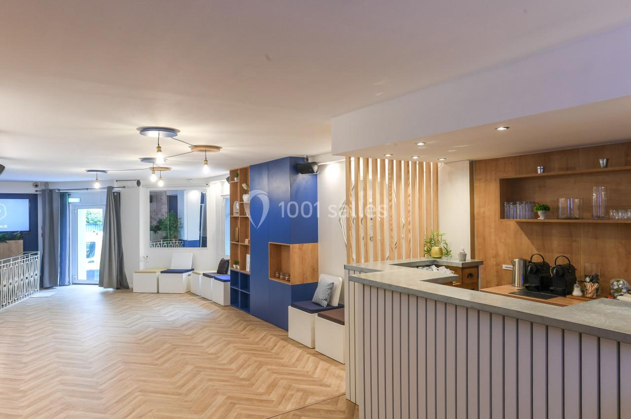 Espace intérieur lumineux avec parquet, comptoir en bois clair, étagères et assises intégrées près des murs.