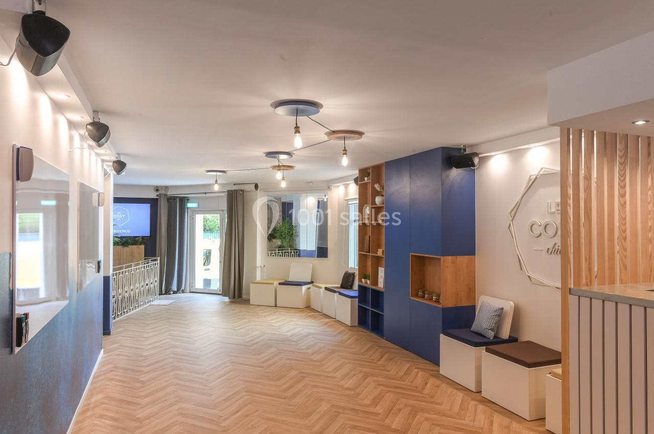 Espace intérieur lumineux avec parquet en chevrons, banquettes, étagères murales et éclairage suspendu moderne.