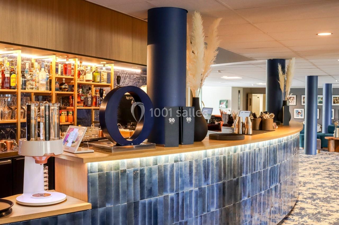 Comptoir de bar moderne avec étagères remplies de bouteilles, décoration contemporaine et lumière chaleureuse.