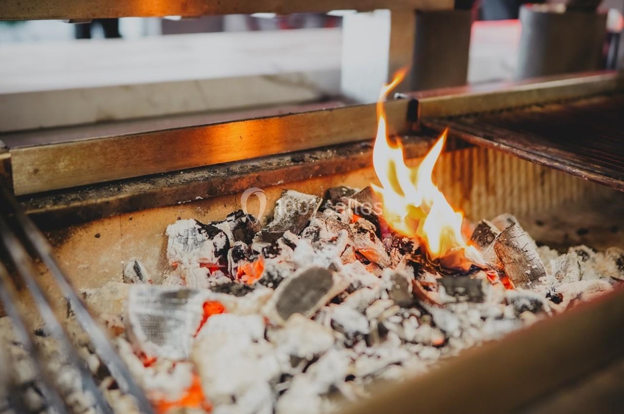 Braises incandescentes et flammes vives dans un foyer en métal, prêt pour une cuisson au barbecue.