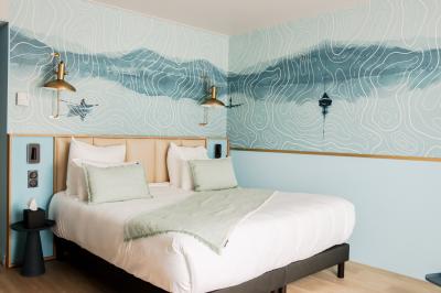 Salle de bain moderne avec lavabo blanc, miroir rond éclairé, robinet noir et carrelage mural texturé.
