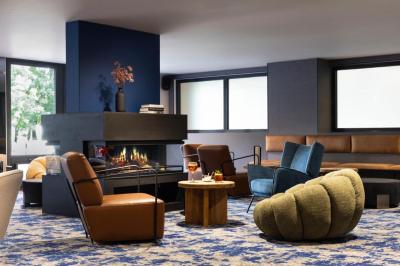 Salle de bain moderne avec lavabo blanc, miroir rond éclairé, robinet noir et carrelage mural texturé.