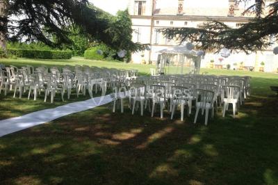 Intérieur d'une tente de réception avec tables rondes décorées, chaises en bois clair et lumière naturelle.