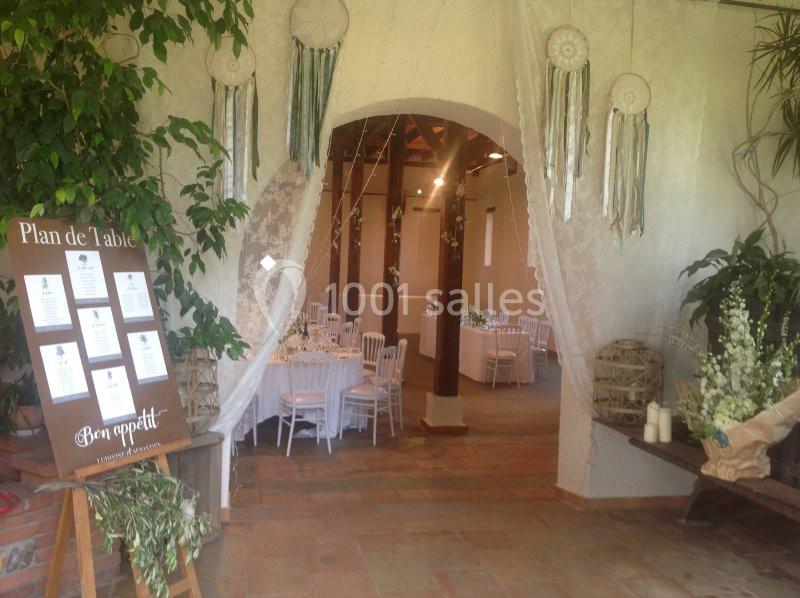 Entrée décorée avec des attrape-rêves et un plan de table, menant à une salle de réception avec des tables dressées.