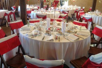 Intérieur d'une tente de réception avec tables rondes décorées, chaises en bois clair et lumière naturelle.