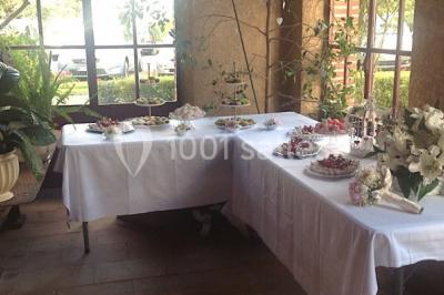 Intérieur d'une tente de réception avec tables rondes décorées, chaises en bois clair et lumière naturelle.