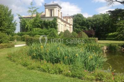 Intérieur d'une tente de réception avec tables rondes décorées, chaises en bois clair et lumière naturelle.