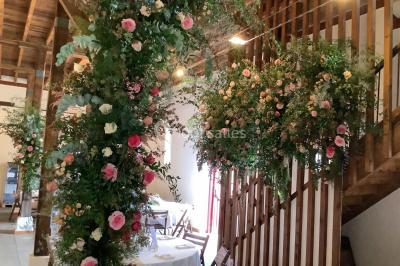 Intérieur d'une tente de réception avec tables rondes décorées, chaises en bois clair et lumière naturelle.