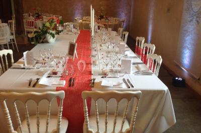 Intérieur d'une tente de réception avec tables rondes décorées, chaises en bois clair et lumière naturelle.