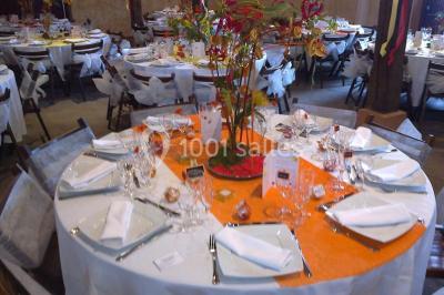 Intérieur d'une tente de réception avec tables rondes décorées, chaises en bois clair et lumière naturelle.