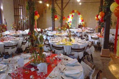 Intérieur d'une tente de réception avec tables rondes décorées, chaises en bois clair et lumière naturelle.