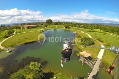 Salle de réception décorée pour un mariage, avec des tables alignées et nappes blanches ornées de nœuds roses.