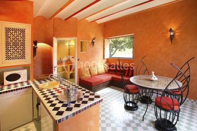 Salle de réception décorée pour un mariage, avec des tables alignées et nappes blanches ornées de nœuds roses.