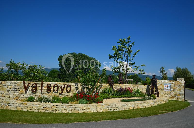 Entrée paysagée avec un muret en pierre, des plantations fleuries, des sculptures et l'inscription ’Val Soyo’.