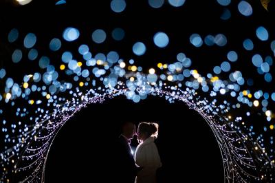 Salle de réception décorée pour un mariage, avec des tables alignées et nappes blanches ornées de nœuds roses.