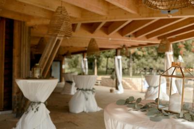 Salle de réception décorée pour un mariage, avec des tables alignées et nappes blanches ornées de nœuds roses.