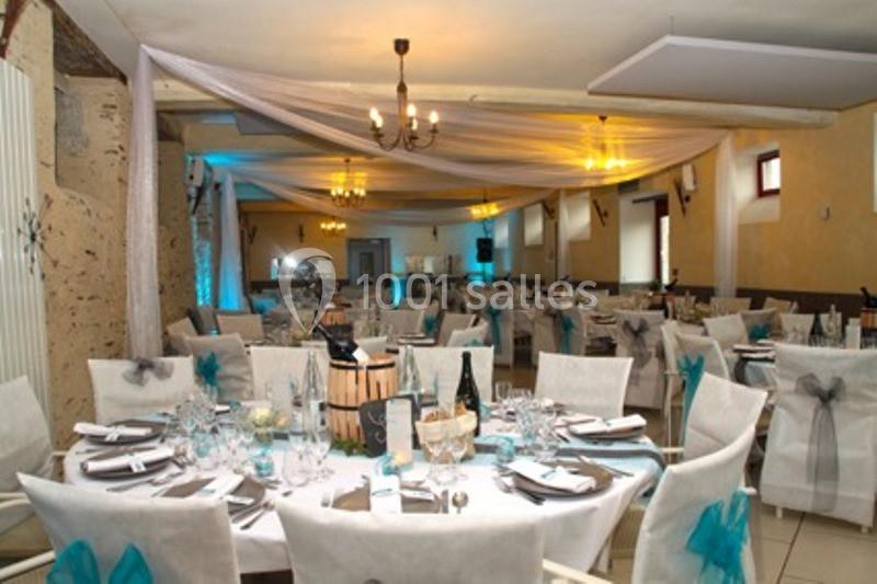 Salle de réception décorée avec des tables rondes dressées, nappes blanches et accents turquoise et gris.