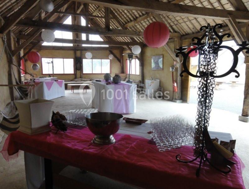 Salle de réception rustique décorée avec des lanternes et une table dressée pour un événement.