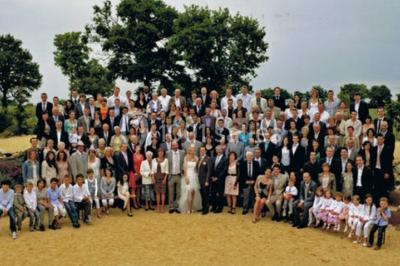 Un grand groupe de personnes posant ensemble en extérieur, devant un paysage verdoyant avec des arbres.