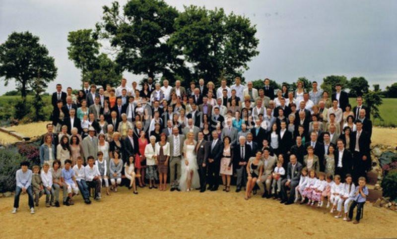 Un grand groupe de personnes posant ensemble en extérieur, devant un paysage verdoyant avec des arbres.