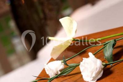 Fleurs blanches posées sur une table en bois, avec un fond flou de lumières et de décorations.