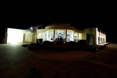 Vue d'une maison moderne avec piscine, statue décorative au premier plan et ciel dégagé en arrière-plan.