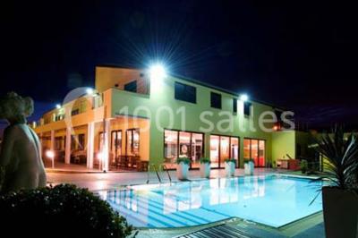 Vue d'une maison moderne avec piscine, statue décorative au premier plan et ciel dégagé en arrière-plan.