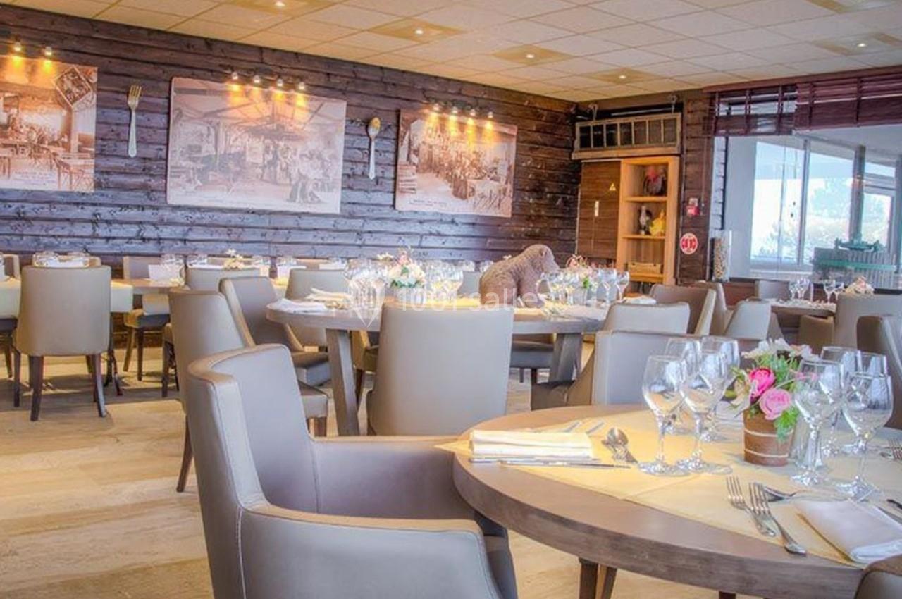 Salle de restaurant lumineuse avec tables dressées, chaises beige clair et décorations murales en bois et photos vintage.