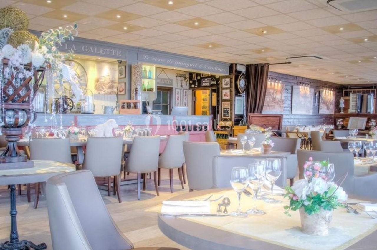 Salle de restaurant lumineuse avec tables dressées, décorations florales et ambiance élégante.