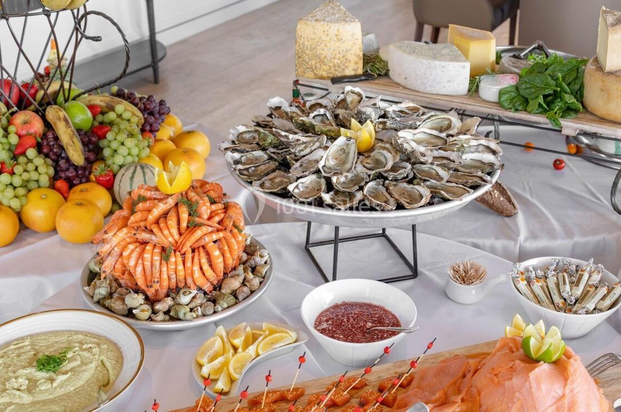 Table garnie de fruits de mer, huîtres, fromages, fruits frais et accompagnements divers.