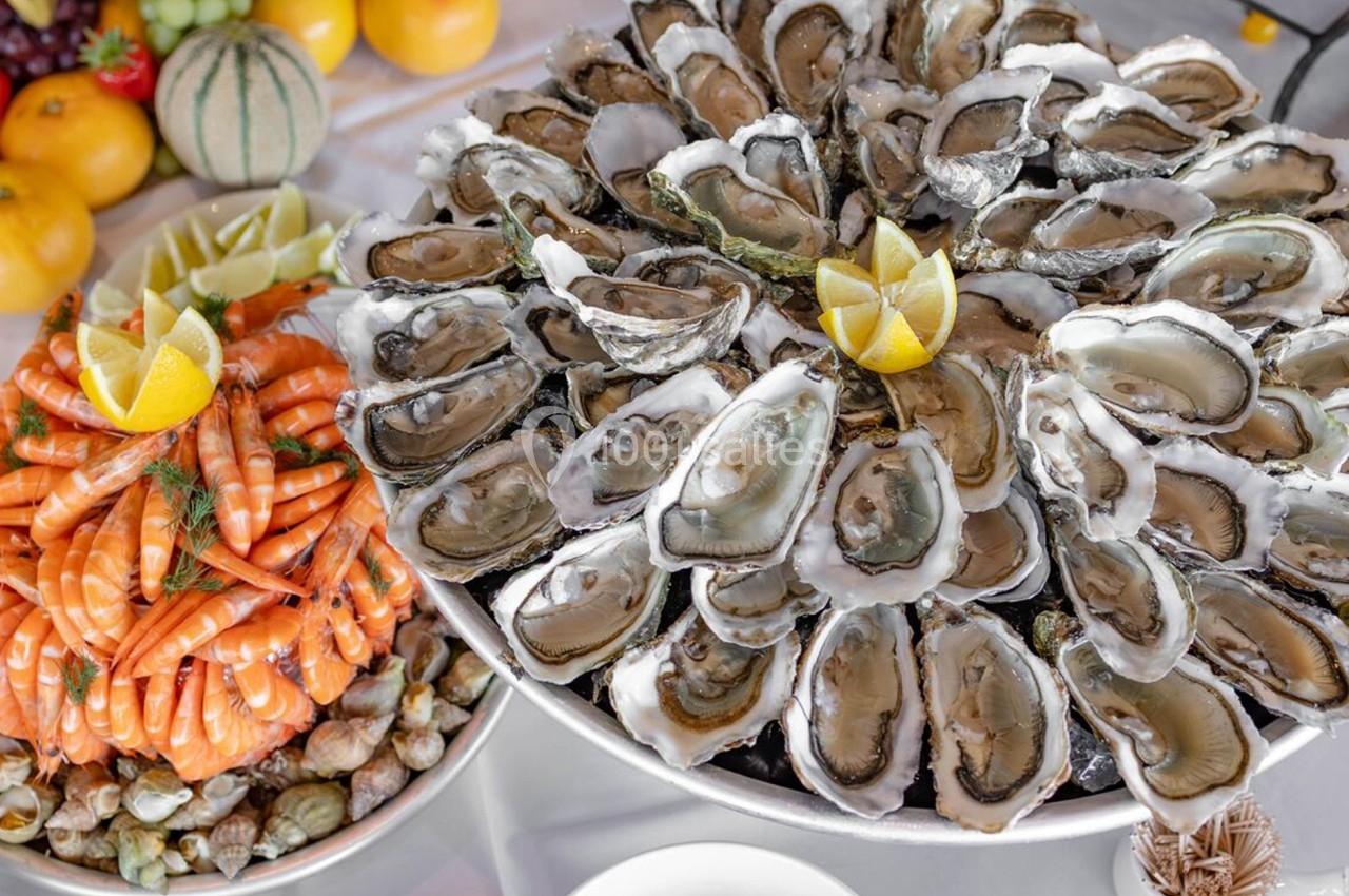 Plateaux de fruits de mer avec huîtres, crevettes, coquillages et citrons, disposés sur une table festive.