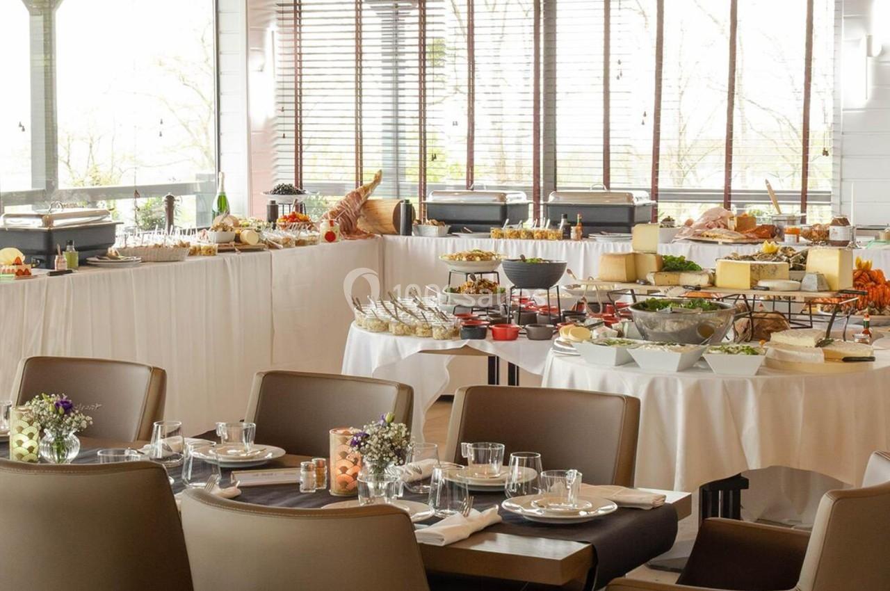 Salle de restaurant avec tables dressées et buffet varié comprenant fruits, fromages et desserts.