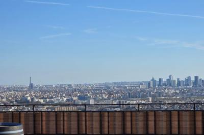 Vue panoramique d'une ville avec la tour Eiffel à gauche et des gratte-ciels modernes à droite sous un ciel dégagé.