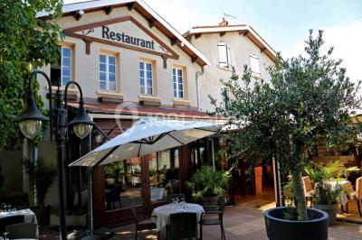 Menu posé sur une table dressée en extérieur, entourée de verres, fleurs et paysage verdoyant en arrière-plan.