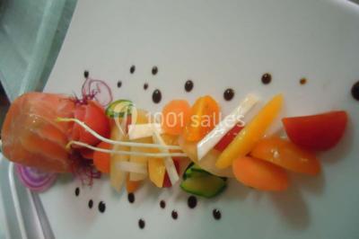 Menu posé sur une table dressée en extérieur, entourée de verres, fleurs et paysage verdoyant en arrière-plan.