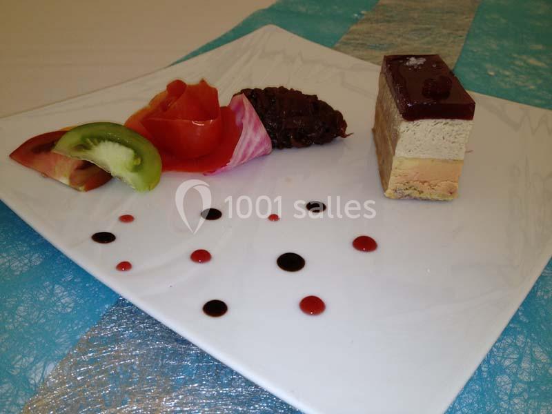 Assiette gastronomique avec terrine, légumes colorés, décoration de sauces et présentation soignée sur une nappe bleue.