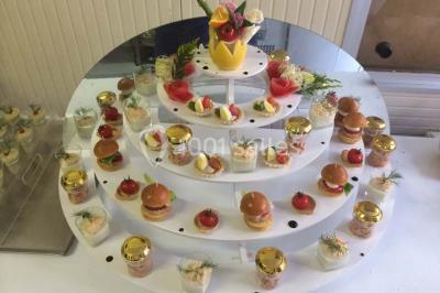 Menu posé sur une table dressée en extérieur, entourée de verres, fleurs et paysage verdoyant en arrière-plan.