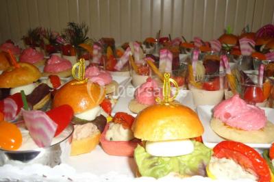 Menu posé sur une table dressée en extérieur, entourée de verres, fleurs et paysage verdoyant en arrière-plan.