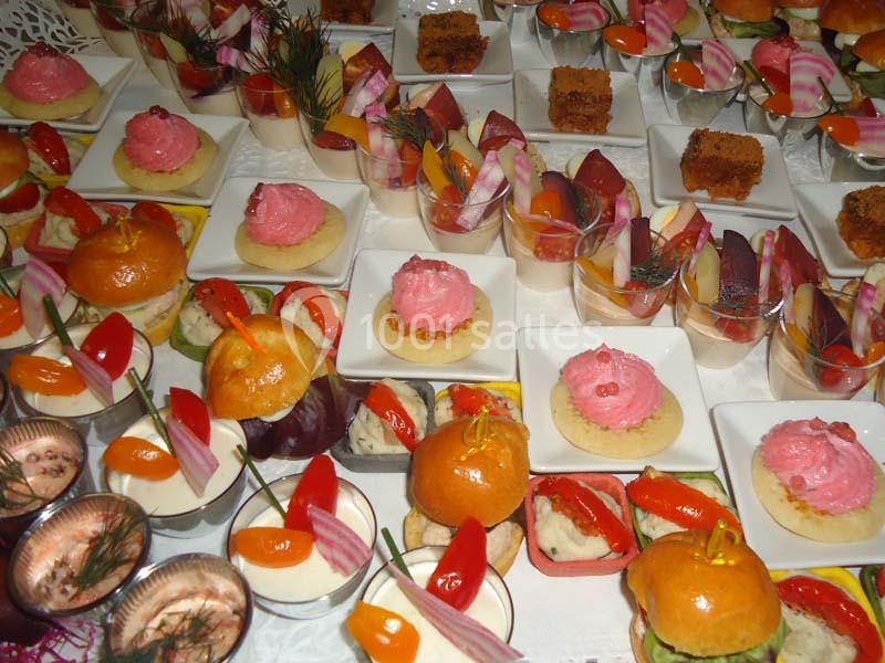 Assortiment de bouchées apéritives colorées disposées sur une table, comprenant verrines, mini-burgers et canapés.