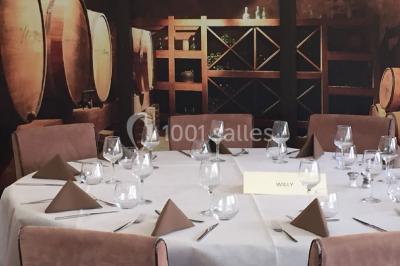 Menu posé sur une table dressée en extérieur, entourée de verres, fleurs et paysage verdoyant en arrière-plan.