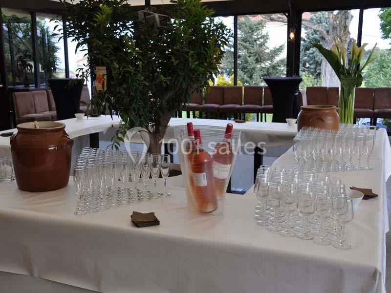 Table dressée avec des verres, des bouteilles de vin rosé dans un seau, et des jarres en terre cuite dans une salle…