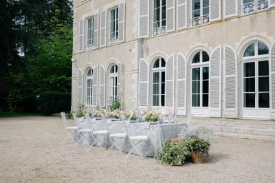 Plaque ’Château de Champvallins’ sur une table en rotin avec une cloche dorée et une boîte décorative.