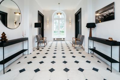 Plaque ’Château de Champvallins’ sur une table en rotin avec une cloche dorée et une boîte décorative.