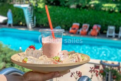 Salle de restaurant élégante avec grandes baies vitrées, tables dressées et luminaires suspendus au plafond.