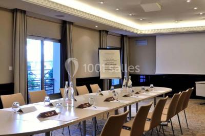 Salle de restaurant élégante avec grandes baies vitrées, tables dressées et luminaires suspendus au plafond.