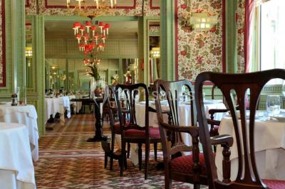 Salle de restaurant élégante avec grandes baies vitrées, tables dressées et luminaires suspendus au plafond.